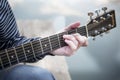 Young guy playing a guitar at sunset on river.Close up his hands and guitar neck . Royalty Free Stock Photo
