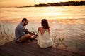 Young guy playing guitar to his girlfriend on the lake Royalty Free Stock Photo