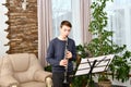 A young guy plays the clarinet from notes. Learning music at home Royalty Free Stock Photo