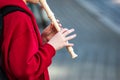 A young guy plays a flute in the evening on the street in the city. Street musician