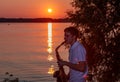 A young guy plays the saxophone in the evening at sunset Royalty Free Stock Photo