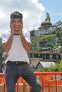 A young guy posing funny sitting on safety barrier beside of lake with beautiful hilly area of Tso-Pema