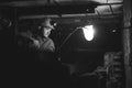 A young guy in a protective suit and helmet sits in a tunnel with a burning scrapbook