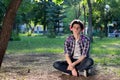 Young guy with purple hair sitting on a skateboard in the park