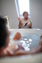 A young guy reading a book to his girlfriend who enjoying the bath. Love, relationship, together Royalty Free Stock Photo