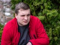 A young guy in a red jacket smokes an electronic cigarette Royalty Free Stock Photo