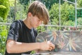 Young guy repairs a skateboard board in the garden