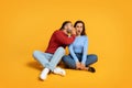 Young guy sharing secret with his girlfriend, yellow background Royalty Free Stock Photo