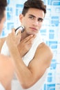 Young guy shaving his beard off with an electric shaver Royalty Free Stock Photo