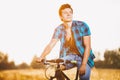 A young guy in a shirt and naked torso sits on a bicycle in headphones and listens to music outdoors, nature, field outside city Royalty Free Stock Photo