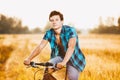 A young guy in a shirt and naked torso sits on a bicycle in headphones and listens to music outdoors, nature, field outside city Royalty Free Stock Photo