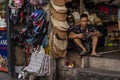 A young guy in shorts, a seller of womens hats and tourist goods in a street shop, plays on his phone.thailand, Phuket Royalty Free Stock Photo