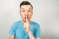 Young guy shut your mouth with finger dressed in a blue t shirt on a light background Royalty Free Stock Photo