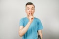 Young guy shut your mouth with finger dressed in a blue t shirt on a light background Royalty Free Stock Photo