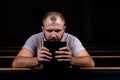 A young guy sits on a church bench, reads the bible and prays. The concept of religion, prayer, faith Royalty Free Stock Photo