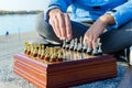 A young guy sits cross-legged and plays chess in the waterfront park. Royalty Free Stock Photo