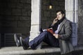 A young guy is sitting on a old window frame in New York City,  reading and talking on the phone Royalty Free Stock Photo