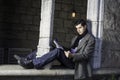 A young guy is sitting on a old window frame In New York City and reading Royalty Free Stock Photo