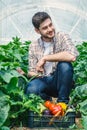 Young guy is sitting between rows of plants. Royalty Free Stock Photo