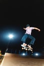 Young guy skateboarder doing a jump trick at night in a skatepark Royalty Free Stock Photo