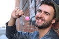 Young guy smiling surrounded by graffiti walls holding a pink lollipop Royalty Free Stock Photo