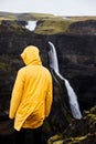 Waterfall Haifoss in Iceland. A young guy stands on a cliff and looks at the waterfall.