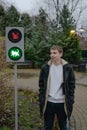 A young guy stands at a traffic light for cats, waiting for a pedestrian crossing Royalty Free Stock Photo