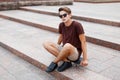 Young guy in a T-shirt with sunglasses and shorts sitting Royalty Free Stock Photo