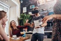 Young guy testing virtual reality headset screaming playing scary game while his cheerful pretty female friends laughing Royalty Free Stock Photo