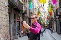 A young guy, a tourist does selfie on a mobile in the street Girona, decorated with colorful shawls, a trip to Spain Royalty Free Stock Photo