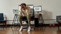 Young guy, trader holding head, feeling depressed after making mistake on stock market, sitting at desk, trading online Royalty Free Stock Photo