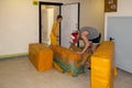 A young guy unpacks large yellow parcels from China in the inter-apartment lobby, and a young beautiful girl in a yellow dress hel