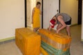 A young guy unpacks large yellow parcels from China in the inter-apartment lobby, and a young beautiful girl in a yellow dress sta