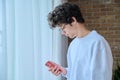 Young guy using smartphone, near window, copy space Royalty Free Stock Photo