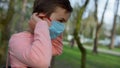 Young guy wearing medical mask in garden. Teen boy walking in mask outdoors Royalty Free Stock Photo