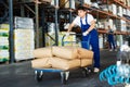 Young guy rolls cart with bags in warehouse Royalty Free Stock Photo