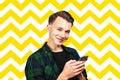 Young guy writes a message on the mobile phone and smiles Royalty Free Stock Photo