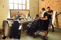 Young guys making haircuts in the hipster style barber shop with grunge walls