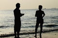 Young guys standing around a sea beach area in the afternoon