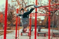 Young gymnast woman at playground hanging upside down on rings and doing splits in park at autumn