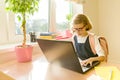 Young hacker little girl in glasses with a school backpack working at the computer, laptop