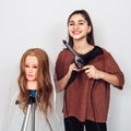 Young hairdresser with a curling iron, hair dryer and a mannequin head on a tripod. Royalty Free Stock Photo