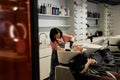 Young Hairstylist Washing Hair of Female Client in Beauty Salon