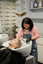 Young Hairstylist Washing Hair of Male Client in Salon Sink