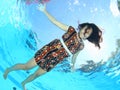 Laughing Papuan woman floating in pool in brown dress Royalty Free Stock Photo