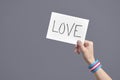 Hand with a transgender flag bracelet holding a paper with a message: love Royalty Free Stock Photo