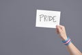 Hand with a transgender flag bracelet holding a paper with a message: pride Royalty Free Stock Photo