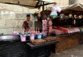 A young handicraftsman of candies, sugar cotton and caramelized apples at his street stall