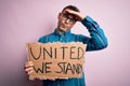 Young handsome activist man asking for union holding banner with united stand message stressed with hand on head, shocked with Royalty Free Stock Photo