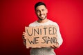 Young handsome activist man protesting holding cardboard with unity message with a happy face standing and smiling with a